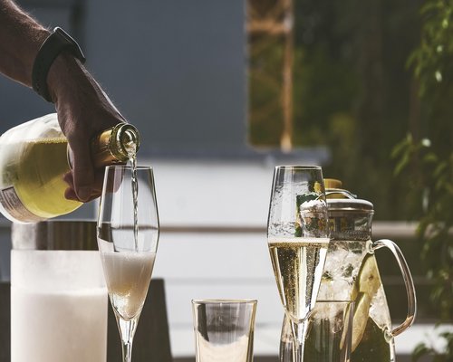 A person pouring a glass of water next to a healthy lunch